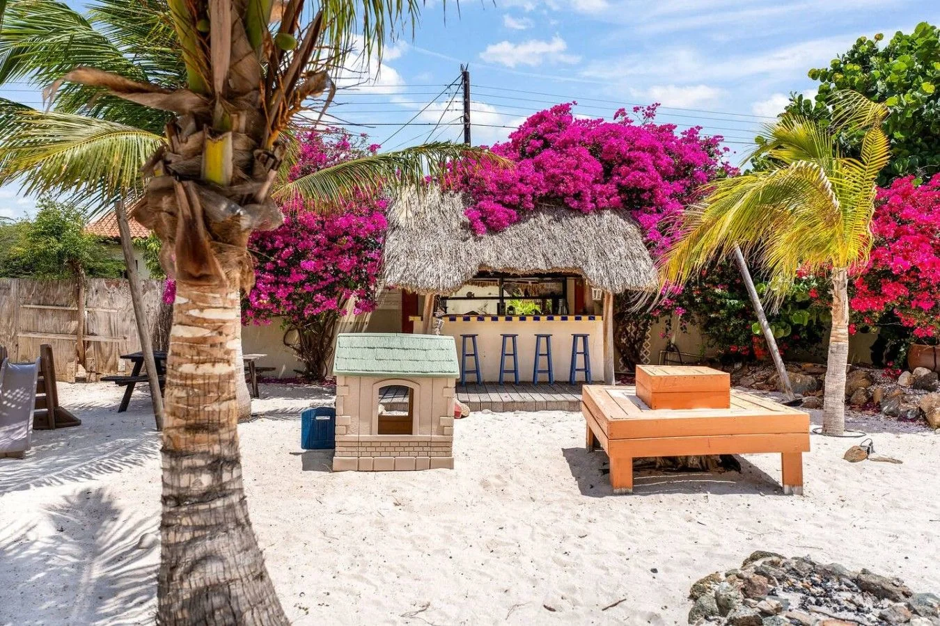 Coconut palms in the sandy garden beside the outdoor bar at Villa Nirvana Aruba